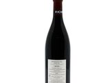 the bottle of red wine is sitting on a white surface