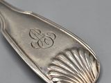 silver spoon with a monogram on it sitting on a gray surface
