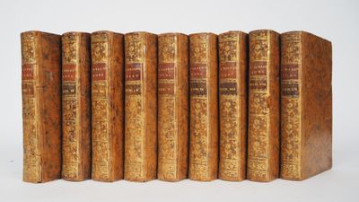 six old books are lined up in a row on a white surface