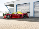 a red and yellow race car parked in front of a garage