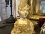 a statue of a woman sitting on a table in front of a mirror