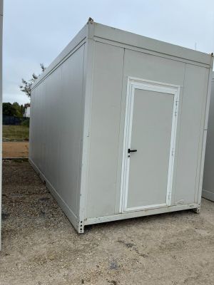 deux conteneurs de stockage blancs posés sur un terrain en terre battue