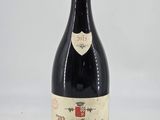 an old bottle of red wine sitting on top of a white table