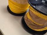 deux bobines de corde jaune posées sur une table, avec des fleurs en arrière-plan