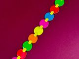 a close up of a colorful bracelet on a pink surface