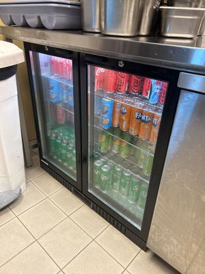 des bouteilles de soda et de boissons gazeuses sont rangées dans le réfrigérateur d'une cuisine