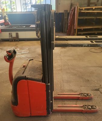un chariot élévateur rouge garé dans un entrepôt avec d'autres équipements