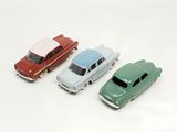 three toy cars are lined up in a row on a white surface