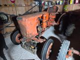 an old orange tractor sitting in a garage