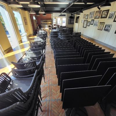 des rangées de chaises noires dans une pièce où sont accrochés des tableaux aux murs
