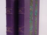two purple books sitting on top of each other on a white surface