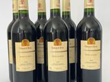 six bouteilles de vin rouge sont alignées sur une surface blanche