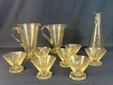 six yellow glass vases and a pitcher sitting on a table