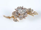 un gros plan sur une broche en forme de fleur en or et diamants