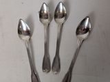 four silver spoons are arranged in a row on a white surface