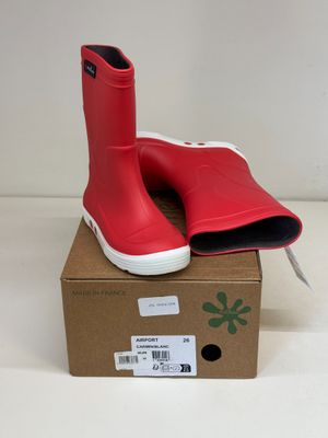 des bottes en caoutchouc rouges posées sur une boîte en carton, sur une surface blanche