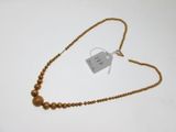 gold beaded necklace with a tag on a white background
