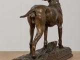 bronze statue of a dog standing on top of a wooden table