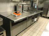 plan de travail en acier inoxydable dans une cuisine professionnelle, avec des appareils électroménagers en arrière-plan
