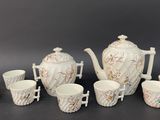 a white tea set with cups and a teapot