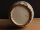 a close up of a white and brown vase on a table
