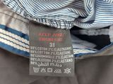 the label is on the pants of a man who is wearing a blue and white striped shirt
