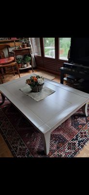 une table basse blanche sur laquelle est posé un vase de fleurs