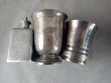 two silver cups and a salt shaker sitting on a table