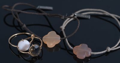 two bracelets with pink and white beads on a black surface
