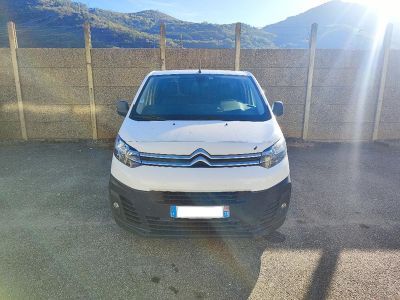 La camionnette blanche est garée sur le parking, à côté d'une clôture.