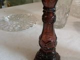 une bougie posée sur une table, à côté d'un vase en verre