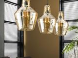 three glass lamps hanging from the ceiling above a wooden table