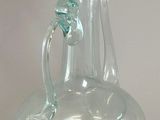 a clear glass vase with a handle on a table