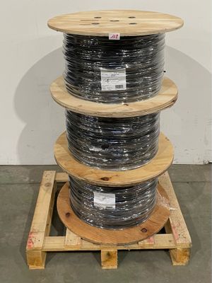 trois bobines de câble sont empilées sur une palette dans un entrepôt