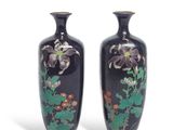 pair of black vases with floral designs on them against a white background