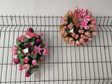 two baskets of flowers on a wire rack on the wall