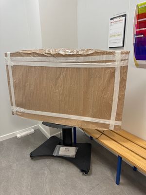 un banc en bois dans une pièce, sur lequel est posé un morceau de carton