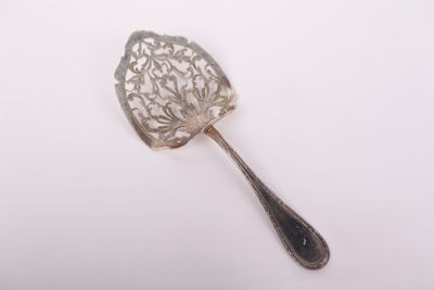 une cuillère en argent ancienne posée sur une surface blanche, avec une cuillère en argent au milieu