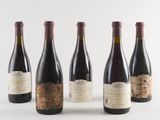 four bottles of wine are lined up on a white surface