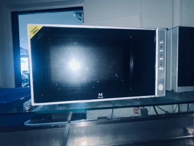 deux micro-ondes posés sur une table en verre dans une pièce