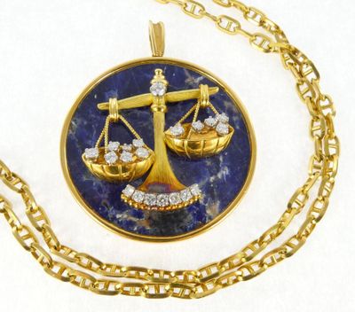 a gold necklace with a picture of a scale of justice on it