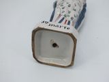 a white and blue vase that has a small hole in it