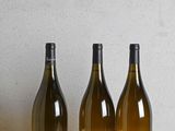 trois bouteilles de vin sont alignées sur une table en bois