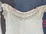 a white shirt with lace on it sitting on a bed