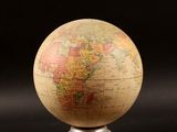 a close up of a small globe on a stand on a black surface
