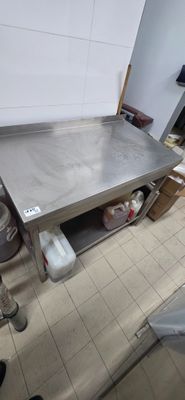 a large stainless steel table in a kitchen with pots and pans on the floor