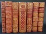 six old books lined up in a row on a black surface