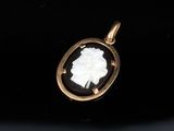 a gold pendant with a cameo of a woman in profile