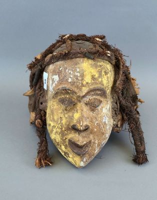 une image représentant un masque en bois avec des dreadlocks et un visage jaune