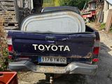a blue toyota pickup truck parked in a yard